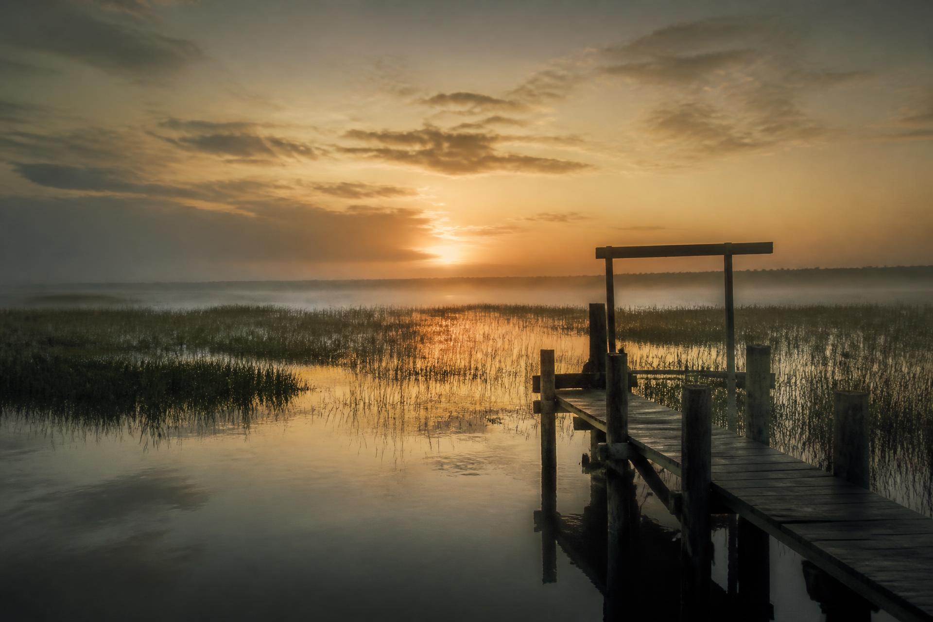 Dawn light over a Louisiana coastal marsh with open water and grass flats
